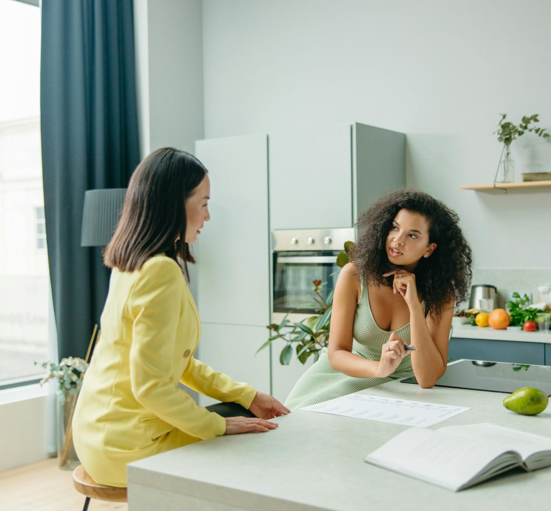Two women engage in a conversation about nutrition in a stylish kitchen setting.